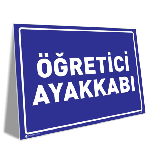 Blue rectangular sign with a white border and bold Turkish text 'ÖĞRETCİ AYAKKABI' on a blue background, tilted slightly to the left.)]